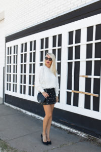 off white fringe sweater, fringe batwing sweater, leather skirt with studs, black leather mini skirt with studded detail, black crossbody bag with chain strap, jaime shrayber