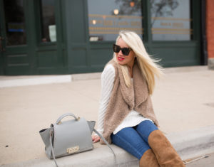 soft fur vest, ribbed ivory sweater, over the knee brown suede boots, medium wash skinny jeans