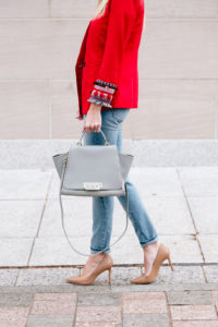 grey top handle bag with gold detail, whiskered medium wash jeans, nude pointed toe stilletos, red one button fitted blazer