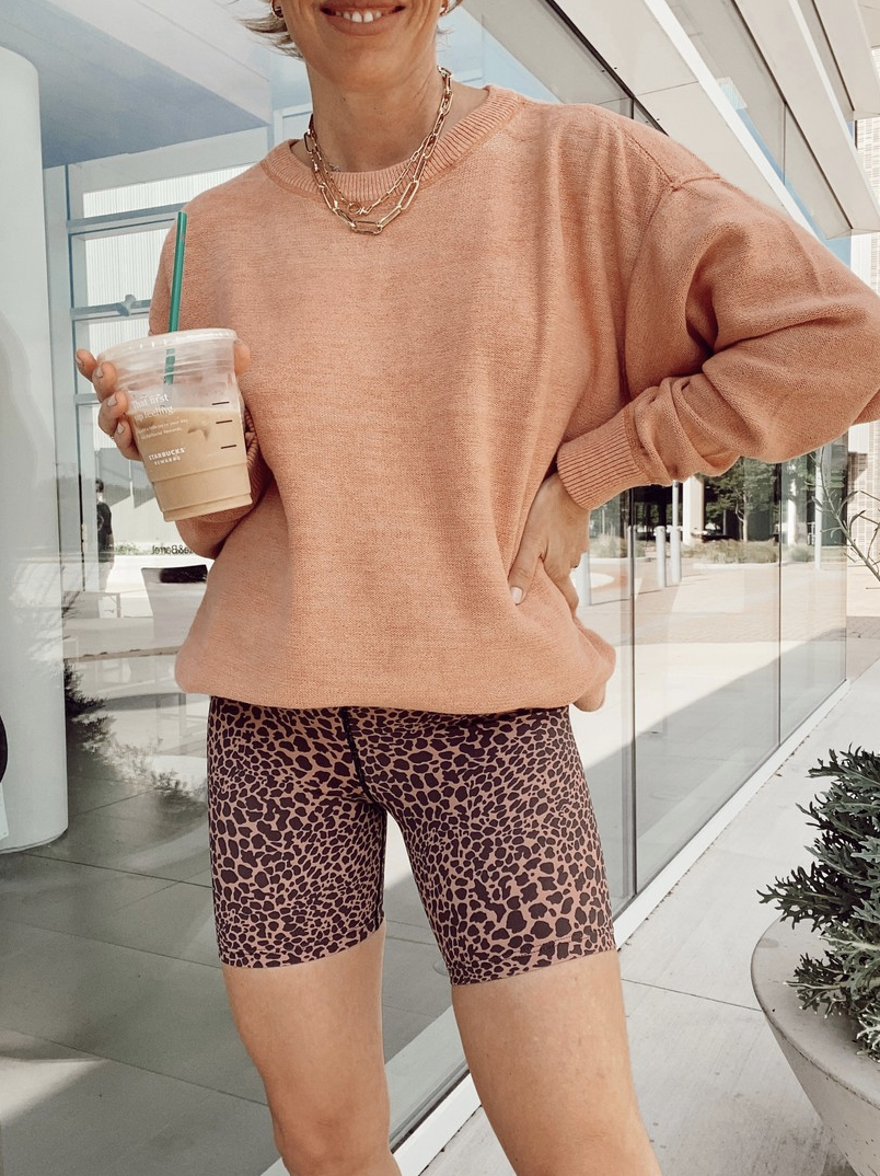 fashion blogger jaime shrayber wearing free people cosmos oversized pullover sweatshirt with brown animal print bike shorts