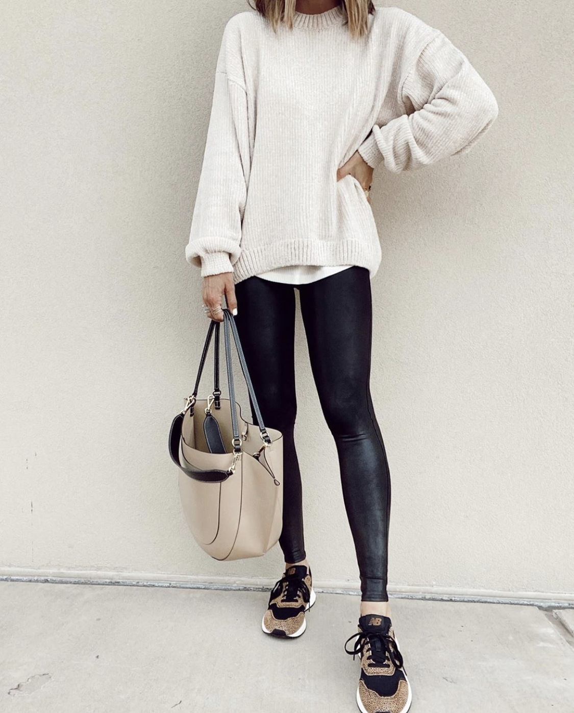 fashion blogger wearing ivory chenille sweater with faux leather leggings and sneakers