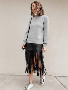 fashion blogger wearing black fringe faux leather midi skirt with sneakers